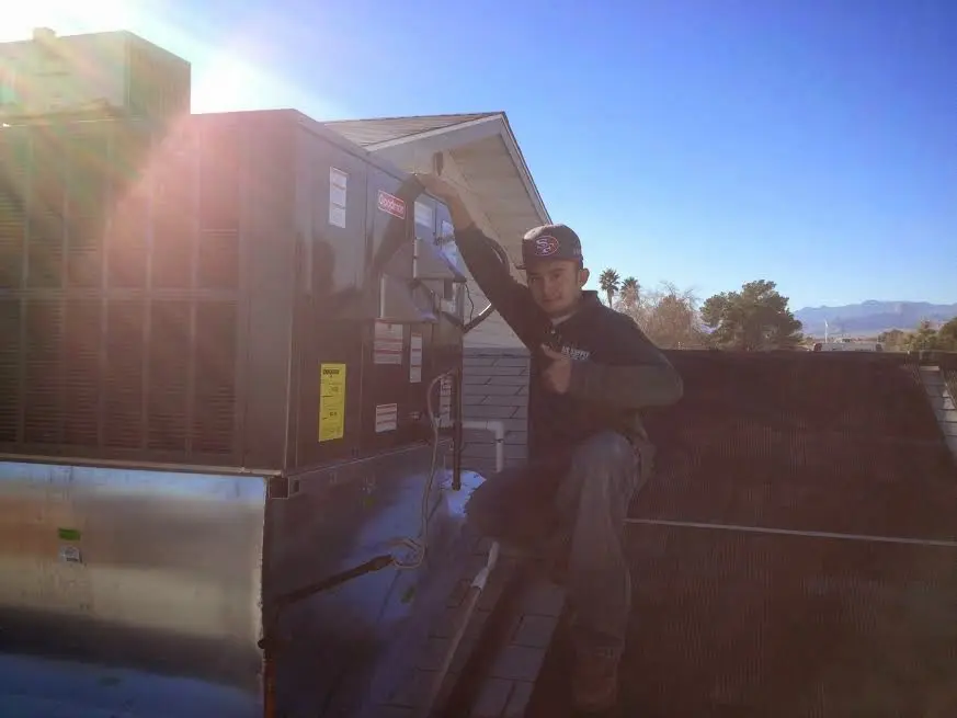 HVAC technician performing AC Tune-Up on a rooftop unit in Covington